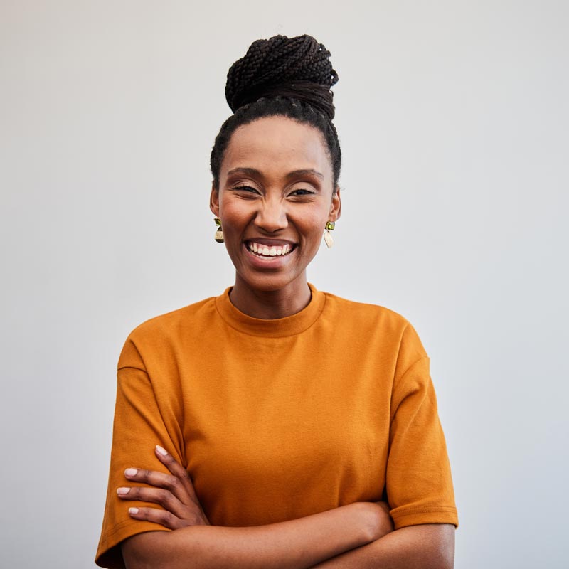 Young businesswoman laughing with her arms crossed against an office wall